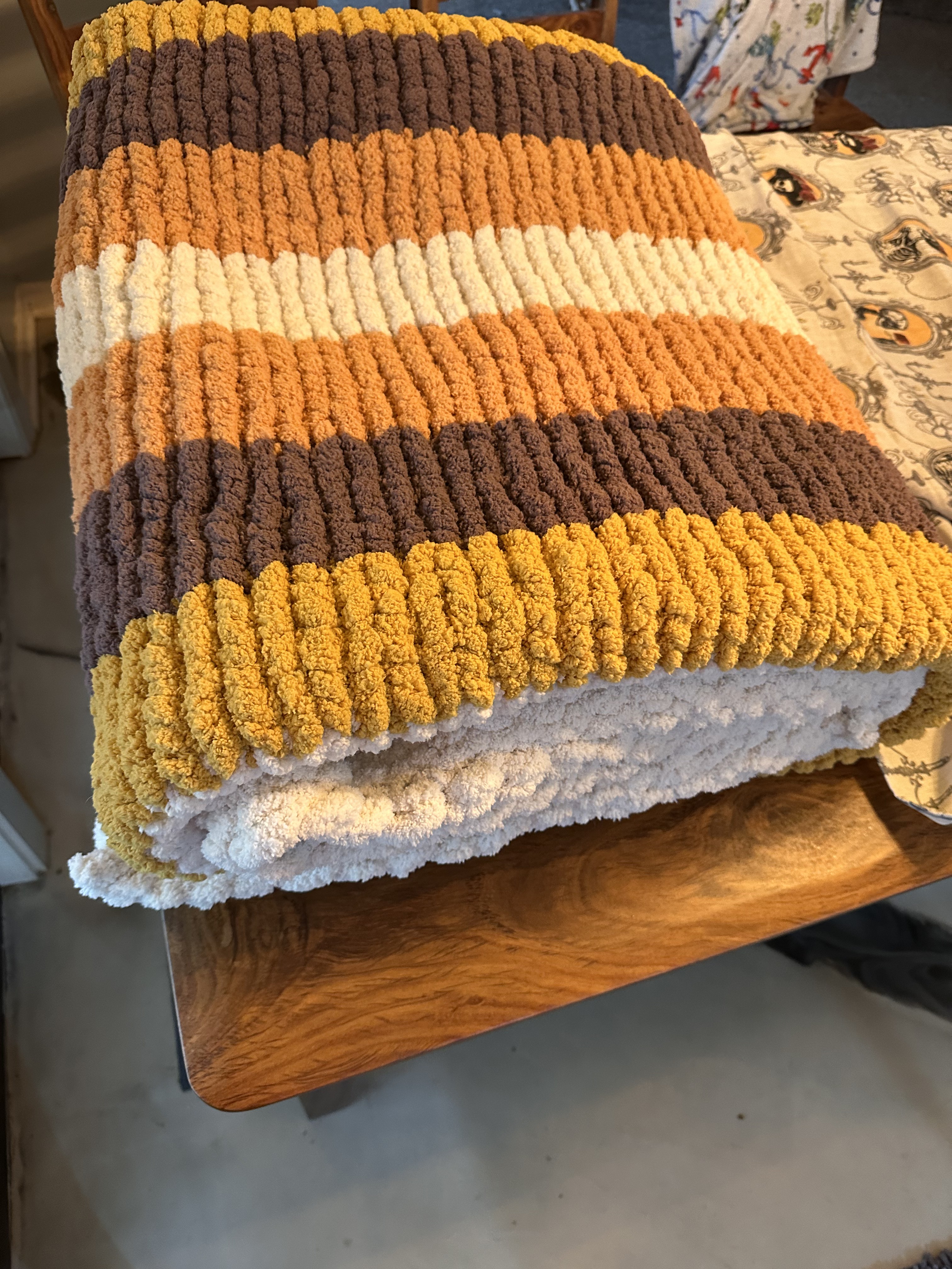 Folded yellow, brown, and cream striped chunky knit throw